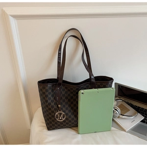 Detailed shot of large brown monogram tote bag showing capacity with a tablet