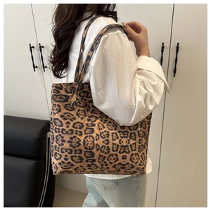 Detail of large leopard print tote bag with long strap shown on model for daily commute