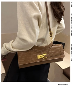 Detail of crocodile pattern texture on brown crossbody bag with gold buckle lock