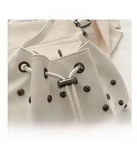 Top view of white PU leather bucket bag featuring drawstring and decorative metal studs