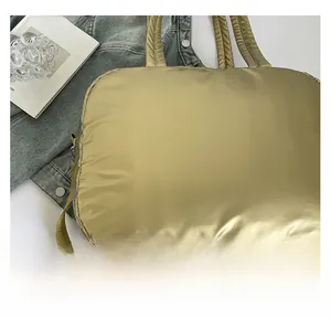 Close-up of metallic gold quilted tote bag with adjustable strap and puffy nylon texture
