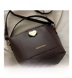 Close-up of brown litchi grain bucket bag with heart-shaped gold lock and wide strap