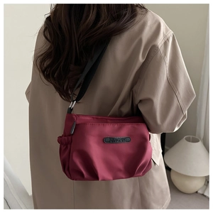 Detail view of burgundy water-resistant nylon shoulder bag with adjustable black strap
