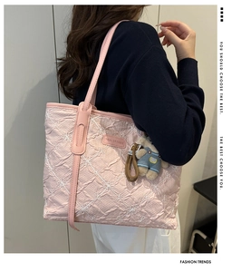 Close-up of pink pleated tote bag featuring white floral embroidery and a cute bear charm