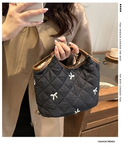 Detail of quilted underarm bag featuring delicate white bow embroidery and brown handle