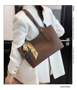 Detail of dark brown leather tote bag with white contrast stitching and silk scarf accessory