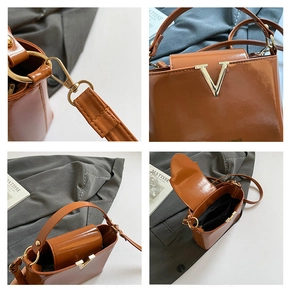 Detail view of brown glossy bucket bag with golden V logo and adjustable shoulder strap