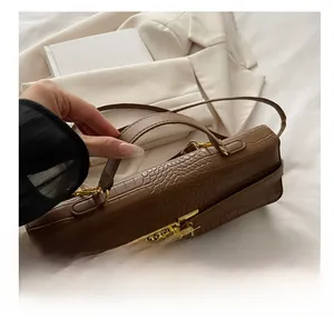 Detail of dark brown crocodile texture handbag with gold metal lock and shoulder strap