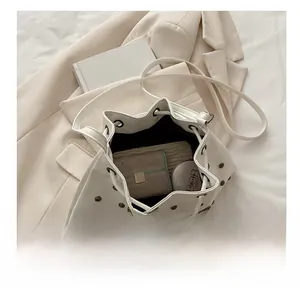 Detail view of large capacity white drawstring bucket bag with rivets and internal storage