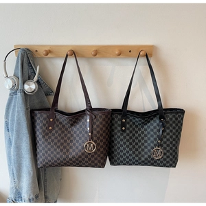 Macro shot of faux leather tote bags with M-pattern print and metallic ring charms