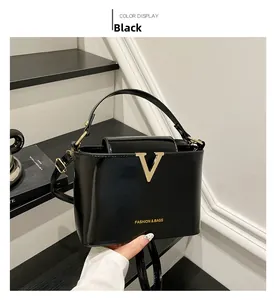 Close-up of black glossy handbag with gold V-metal buckle and elegant lettering