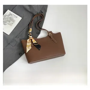 Brown leather tote bag with geometric silk scarf detail next to a Matisse art book