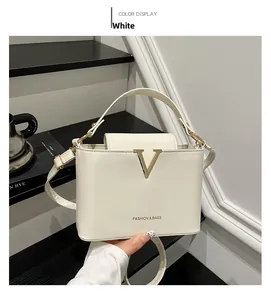 Detailed view of white PU leather handbag with gold V logo and slim shoulder strap
