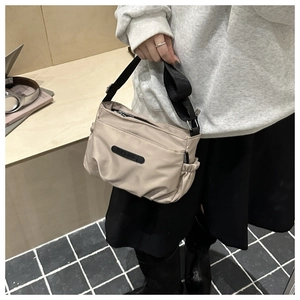 Detail of beige nylon crossbody bag featuring pleated cloud design and adjustable strap