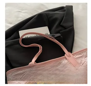 Detailed view of pink floral embroidered tote bag with plush bear charm and leather strap