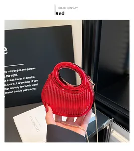 Detail of red acrylic mini bag featuring glossy vertical stripes and a gold chain strap