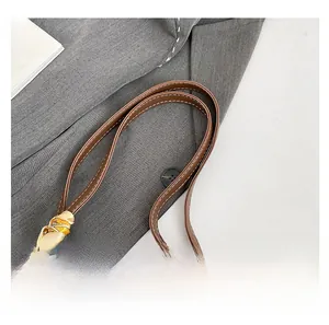 Close-up of brown leather handle with white stitching and decorative silk scarf detail
