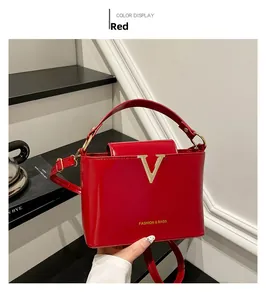 Detail of red patent leather handbag featuring golden V hardware and removable strap