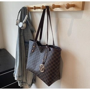 Close-up of large coffee tote bag with M-pattern print and gold metallic charm