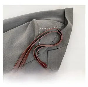 Detalle de bolso tote de ante marrón con asa de cuero y cadena de metal dorada