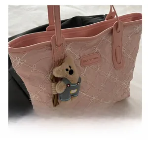 Detail of pink floral embroidered tote bag with bear charm and leather handles