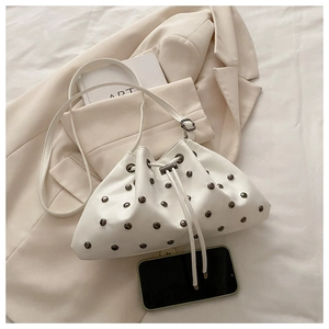 Detail of white drawstring bucket bag with silver studs and premium matte leather texture