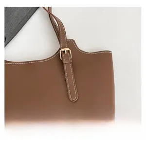Detail of dark brown bucket bag featuring contrast white stitching and gold buckle