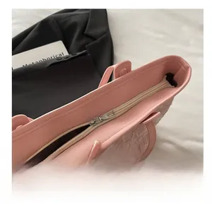 Detail of pink tote bag showing smooth silver zipper and textured lace side accents