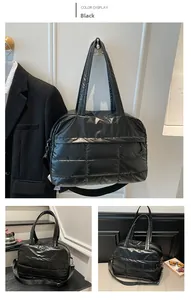 Detail of black quilted shoulder bag featuring glossy fabric and detachable strap