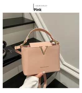 Close-up of pink bucket bag with golden V-shaped buckle and fine leather texture