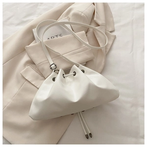 Detail of off-white drawstring bucket bag with rivets on a stylish beige blazer