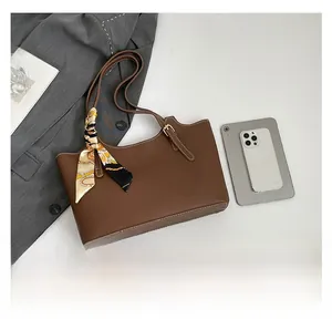 Close-up of brown leather tote bag with white stitching and decorative silk scarf