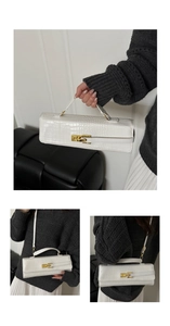 Macro shot of white crocodile embossed baguette bag with gold lock and adjustable strap