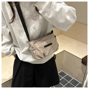 Detail of beige pleated nylon crossbody bag with black adjustable wide strap for daily use