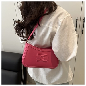 Detail of rose pink underarm bag featuring embossed letter G and smooth faux leather