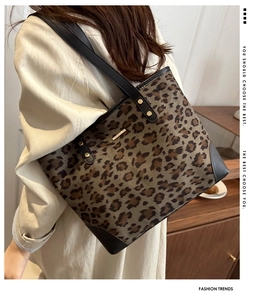 Close-up of leopard print tote with black leather trim and elegant gold hardware