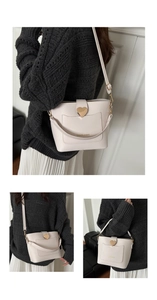 Détail d'un sac seau en similicuir crème avec boucle cœur et lettrage doré chic