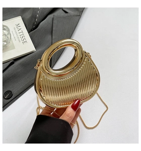 Detail of gold metallic evening bag with vertical stripe texture and round handle