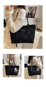 Detail of black tote bag with quilted texture, logo patch and cute bear keychain