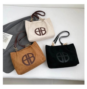 Détail de sacs cabas en daim avec bandoulière chaîne dorée et logo embossé chic