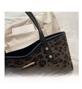Detail of leopard print tote bag featuring gold metal accents and rivet reinforcement