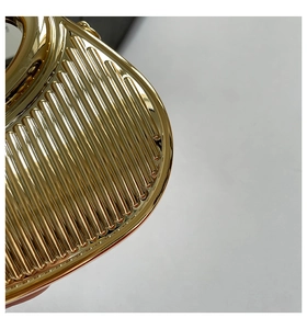 Detailed macro view showing the textured gold metal ribbed pattern on the elegant evening clutch