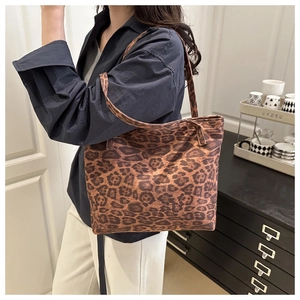 Detailed view of the large leopard print tote bag worn on shoulder by a model