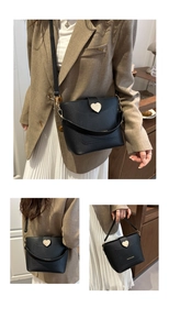 Détail du sac seau noir en cuir grainé avec boucle cœur dorée et sangle tendance