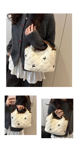 Detail of white quilted tote with black bow embroidery and dark brown leather handles