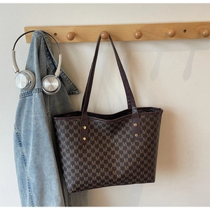 Detail of vintage monogram pattern tote bag with leather straps and gold rivets