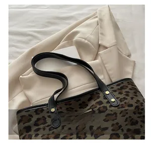 Detail of leopard print tote bag showing black leather handles and gold rivet accents