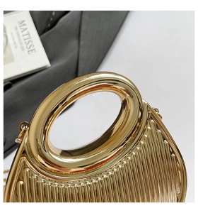 Close-up of golden metal handbag with vertical ridges and oval handle on Matisse book
