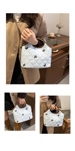 Detail of white quilted tote bag featuring black bow patterns and brown leather handles