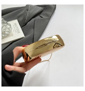 Detail of gold evening clutch with vertical stripe texture and elegant metal chain strap